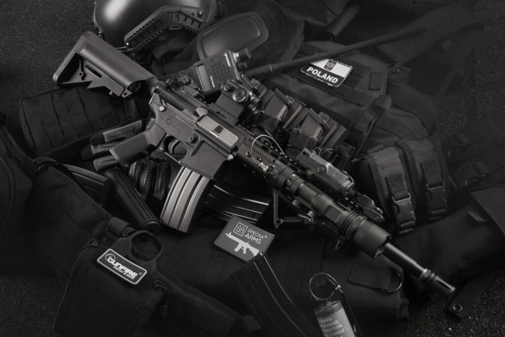 Close-up of tactical military gear including a rifle, radio, and vest on a dark background.
