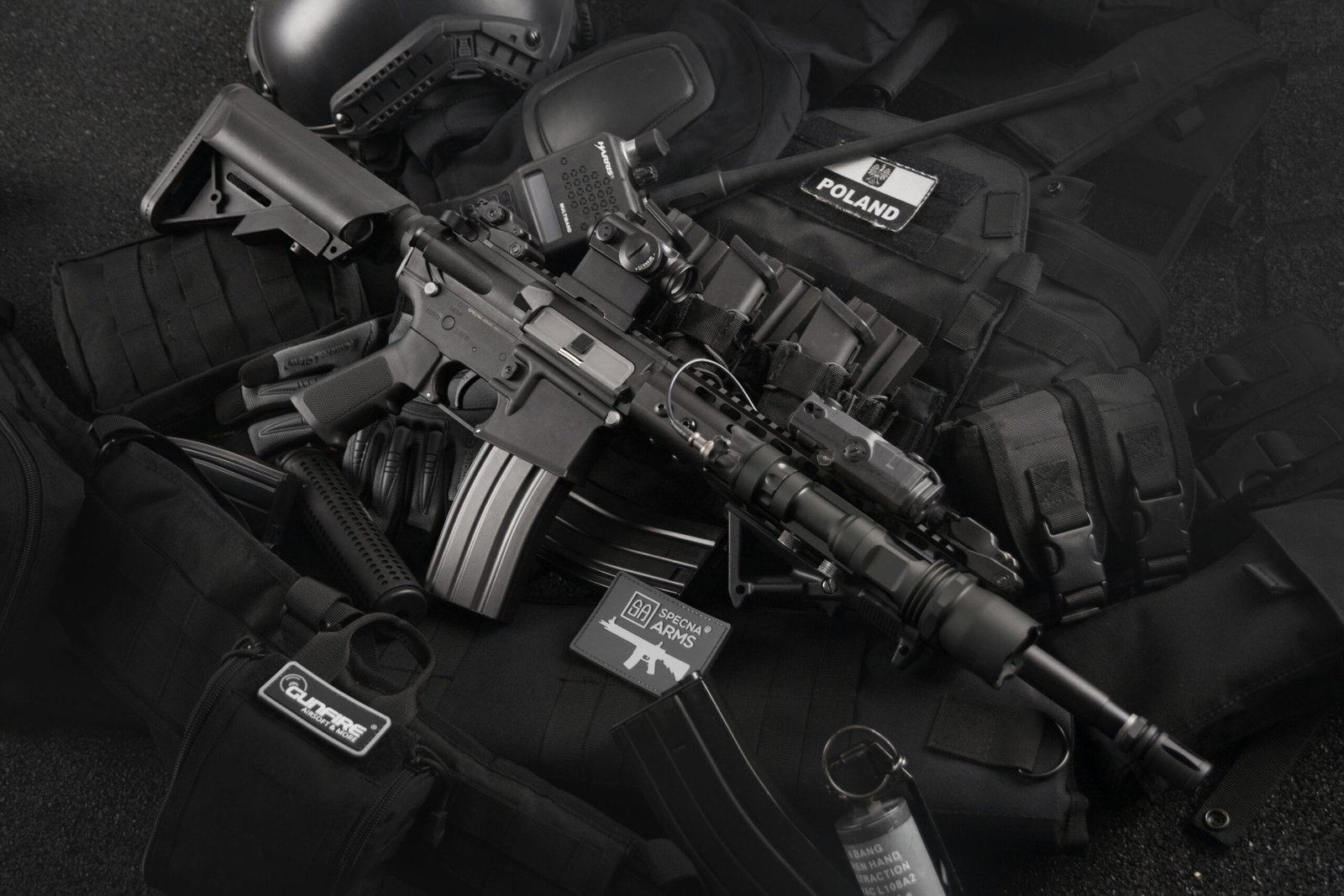 Home Close-up of tactical military gear including a rifle, radio, and vest on a dark background.